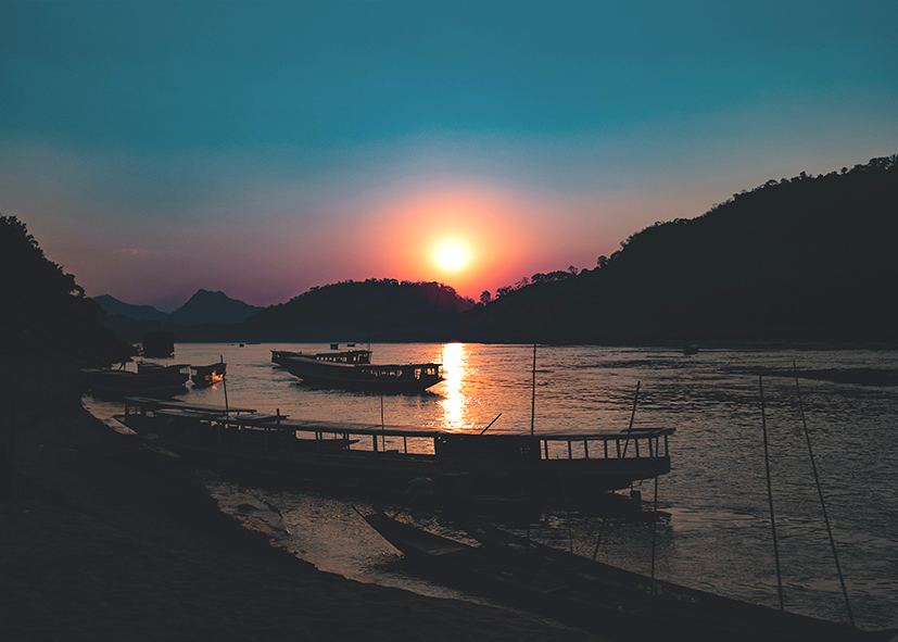 Coucher de soleil sur les bateaux sur les rives du Mékong, voyage au Laos avec une agence Nirvatravel